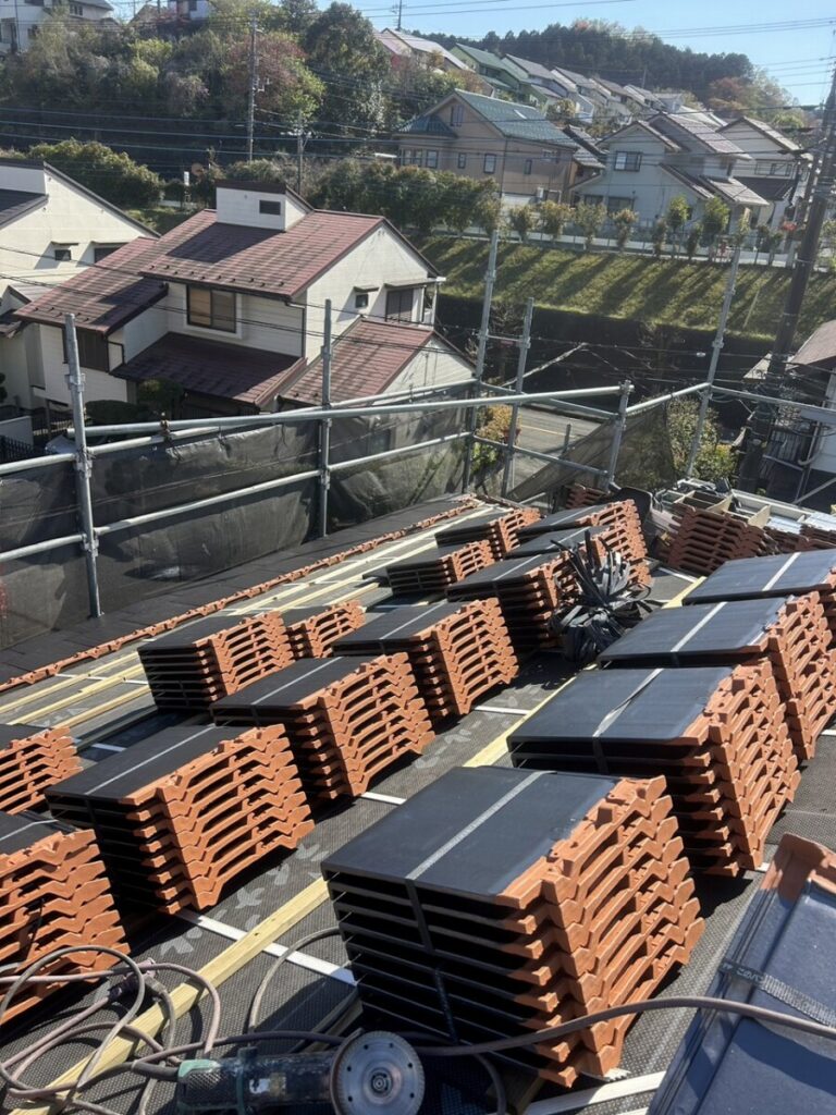 瓦屋根葺き替え工事で屋根上にこれから葺く新規の平板瓦が荷揚げされている写真